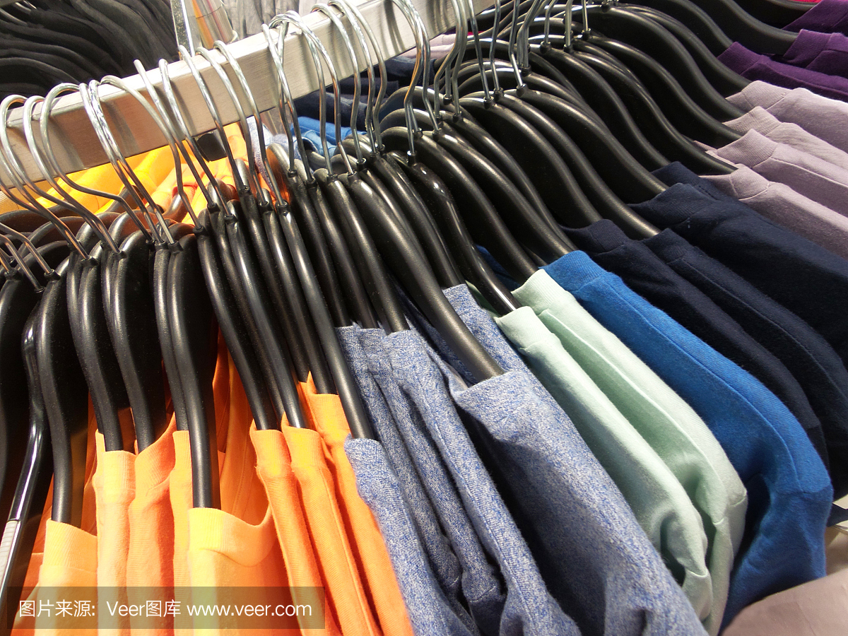 彩虹色的衣服挂在零售店的衣架上。时尚与购物概念